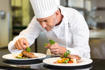 Concentrated male chef garnishing food in kitchen - obrazy, fototapety, plakaty