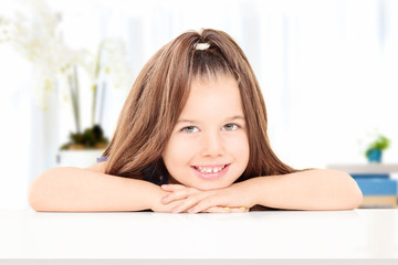 Adorable little girl posing seated at a table