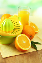 Citrus press and oranges on table on blue background