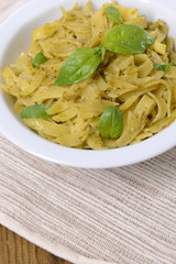Delicious pasta with pesto on plate on table close-up