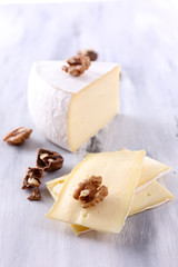 Tasty Camembert cheese with nuts, on wooden table