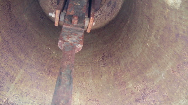 Interior of a big bell up-close image of the rusty bell clapper