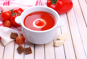 Tasty tomato soup and vegetables on wooden table