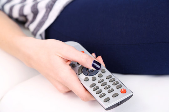 Female hand with TV remote control, close-up