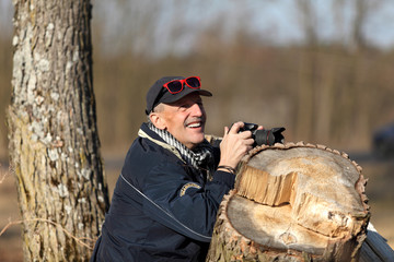 Mężczyzna w starszym wieku fotografuje przyrodę. - obrazy, fototapety, plakaty