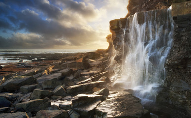 Beautiful landscape image waterfall flowing into rocks on beach