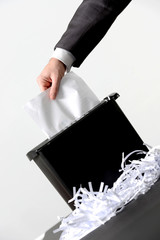 Hand of businessman putting a document in paper shredder