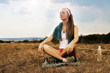 Sporty woman with headphones meditates