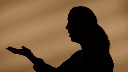 Female silhouette talking with hands. You or me? I don't know!