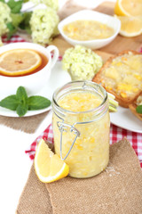 Tasty lemon jam with cup of tea on table close-up