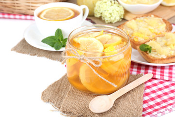 Tasty lemon jam with cup of tea on table close-up