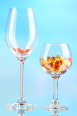 Goblets with pills on blue background