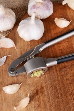 Garlic press with garlic on wooden background