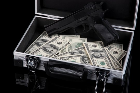 Case with money and gun, isolated on black