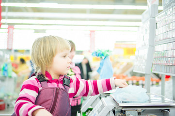 Fototapeta na wymiar Adorable girl weighting fruits in bag on electronic scales in su