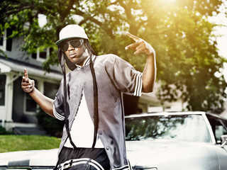 young black man making hand signs in front of car