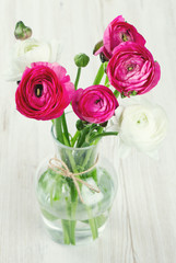 ranunculus flowers in a glass vase on wooden table
