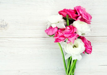 pink and white ranunculus flowers on woode surface