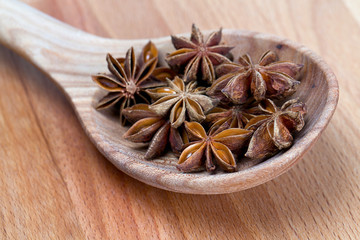 star anise in a spoon on wooden surface