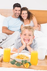 Obraz na płótnie Canvas Smiling young family having breakfast in bed