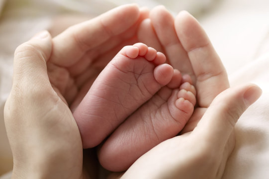 mother hold feets of newborn child
