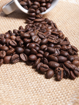 white cup with coffee beans on burlap background.