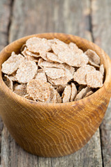 bran flakes in a wooden bowl on wooden table