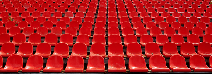 Rijen rode voetbalstadionstoelen met nummers.