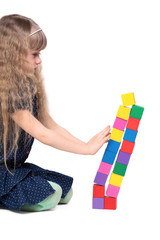 Adorable little girl push a brick toy tower isolated on white ba