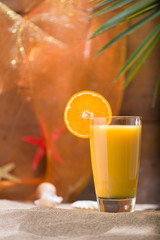 Glass of orange juice on a beach table