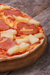 Hawaiian pizza on an old wooden table macro. vertical