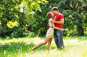 Young beautiful couple. Laugh and kiss. Summer green park