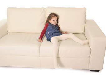 angry broed little girl with long hair lying on sofa
