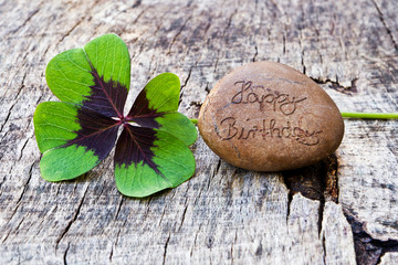 Kleeblatt mit Stein auf Holz, Herzlichen Glückwunsch