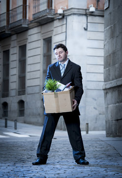 frustrated business man on street fired carrying cardboard box