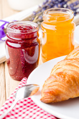 Raspberry and orange jam with croissant. Shallow depth of field.