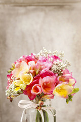 Bouquet of colorful freesia flowers in transparent glass vase.