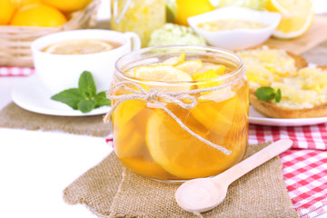Tasty lemon jam with cup of tea on table close-up