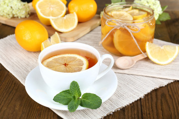 Tasty lemon jam with cup of tea on table close-up