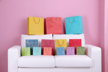 Colorful shopping bags on sofa, on color wall background