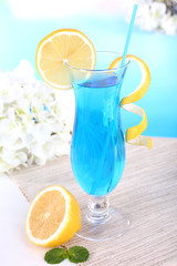 Glass of cocktail on table on light blue background