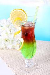 Glass of cocktail on table on light blue background