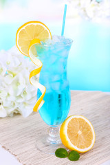 Glass of cocktail on table on light blue background