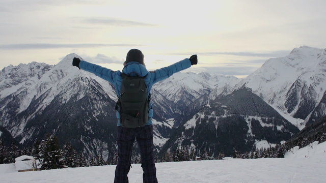 Woman standing on mountain peak with arms outstretched, Alps