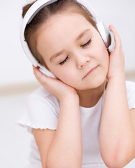 Fototapeta na wymiar Little girl is enjoying music using headphones