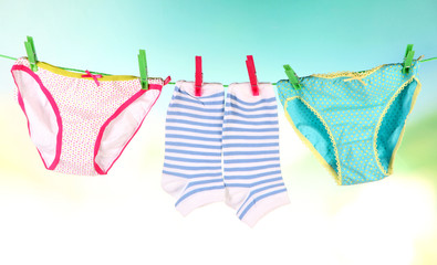 Baby clothes hanging on clothesline, on bright background