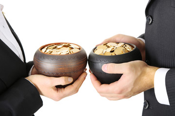 Two ceramic pots with golden coins in male and female hands,