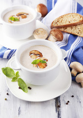 Mushroom soup in white pots, on napkin, on wooden background