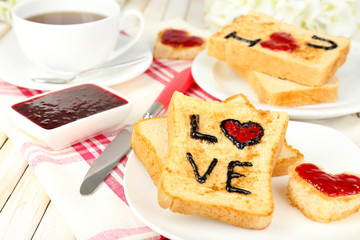 Delicious toast with jam and cup of tea on table close-up