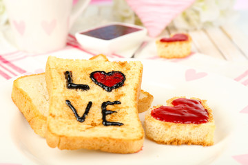 Delicious toast with jam and cup of tea on table close-up